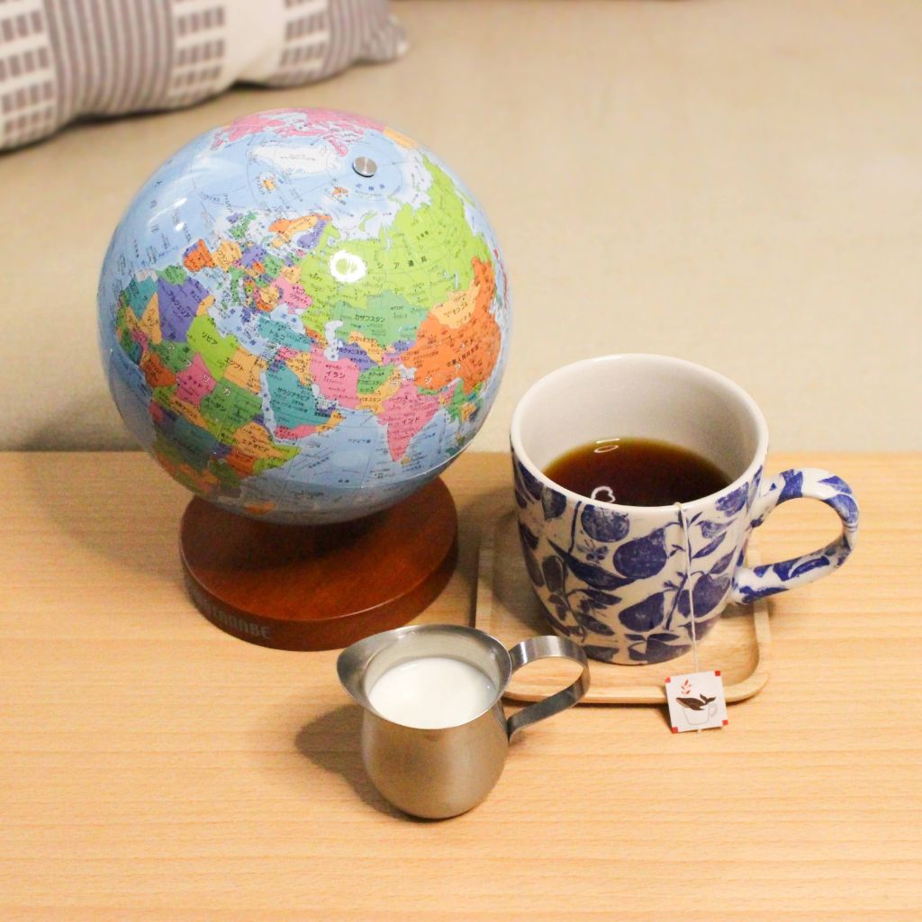 マグカップ入りの紅茶、ミルクピッチャー地球儀の写真